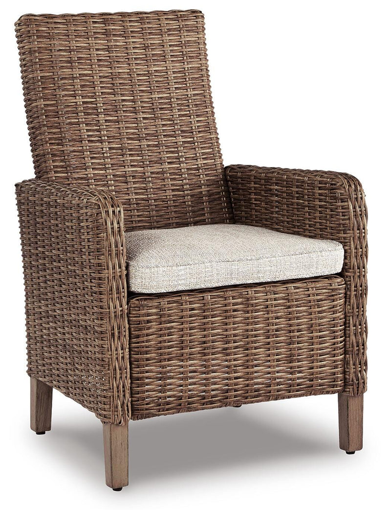 Ashley Furniture Beachcroft outdoor dining set with a round table and six chairs, set on a patio with greenery in the background.