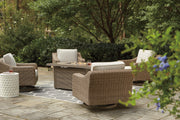 Outdoor Ashley Furniture Beachcroft fire pit table with four Nuvella swivel lounge chairs on patio, perfect for outdoor gatherings.