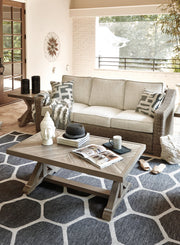 Ashley Furniture Beachcroft outdoor conversation set with cushioned seats, coffee table, and weather-resistant wicker furniture.