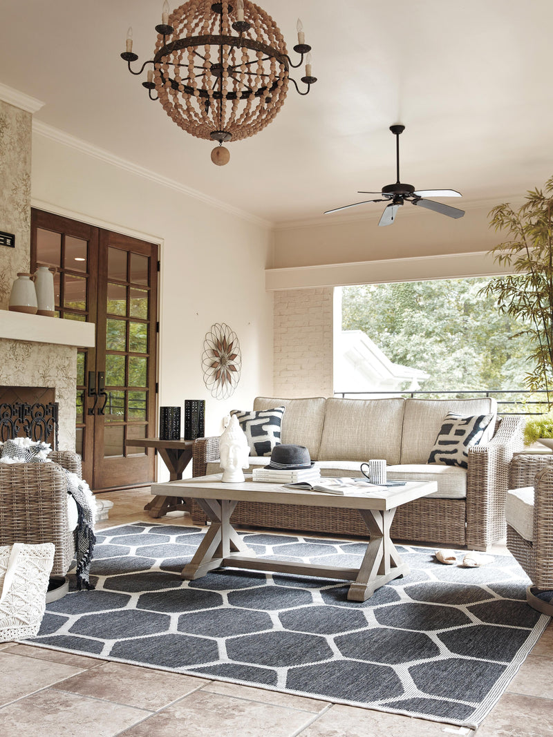 Outdoor Ashley Furniture Beachcroft outdoor conversation set with cushioned seats and coffee table, perfect for relaxing outside.