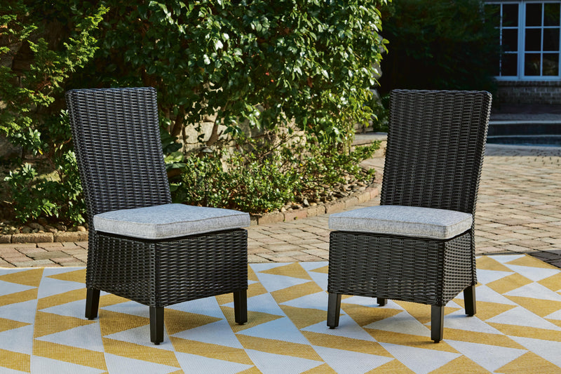 Set of two Ashley Furniture Beachcroft outdoor dining side chairs with cushions, featuring metal frames and woven design.