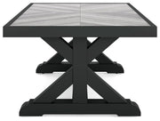 Ashley Furniture Beachcroft outdoor cocktail table with a rectangular wooden top and metal frame, designed for outdoor patio use.