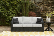 Ashley Furniture Beachcroft outdoor sofa with beige cushions, featuring a stylish wicker design for patio relaxation.