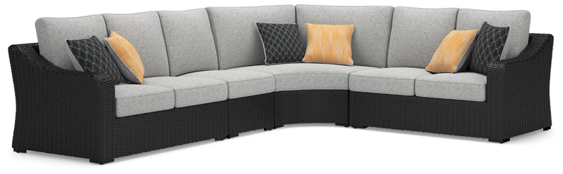 Ashley Furniture Beachcroft outdoor sectional with beige cushions and woven rattan frame, shown from an angled perspective.