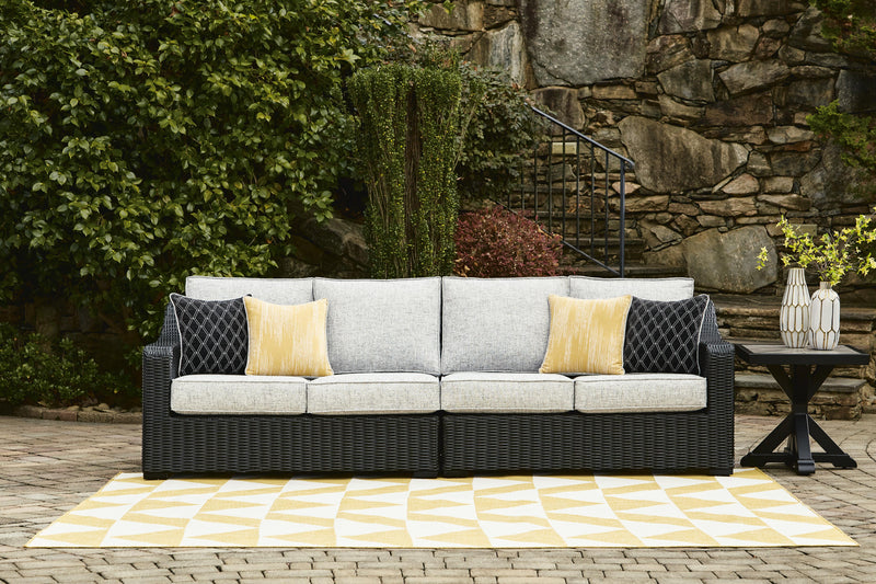 Ashley Furniture Beachcroft 2-piece outdoor sectional loveseat with cushions, featuring woven rattan design and plush seating.