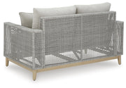 Outdoor Seton Creek outdoor seating set by Ashley Furniture with cushioned chairs and a matching table on a patio.