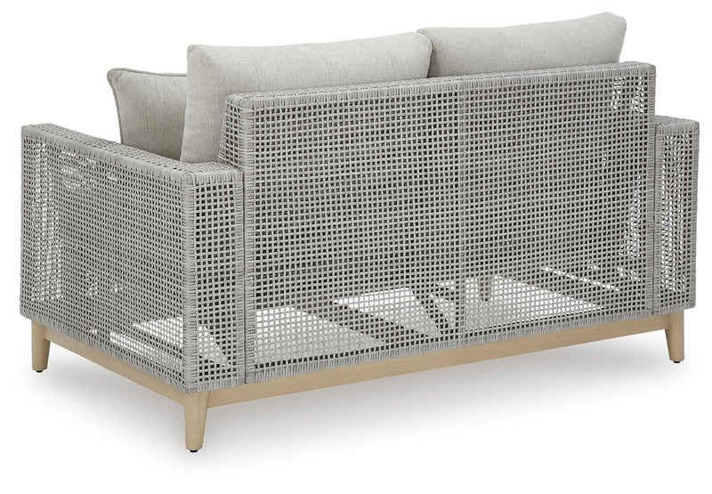 Outdoor Seton Creek outdoor seating set by Ashley Furniture with cushioned chairs and a matching table on a patio.