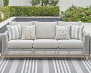 Ashley Furniture Seton Creek outdoor upholstery table set with cushioned chairs and matching table in a garden setting.