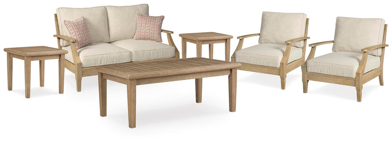 Ashley Furniture Clare View outdoor seating set with cushioned chairs and a matching table in a backyard setting.