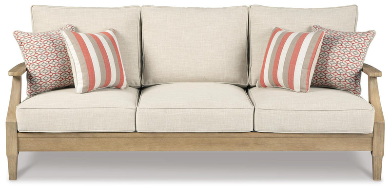 Ashley Furniture Clare View outdoor seating set with cushioned chairs and a glass-top table in a garden setting.
