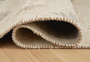 Ashley Furniture Calkin Rug with intricate pattern and neutral tones, rolled out showing detailed woven design on soft fabric.