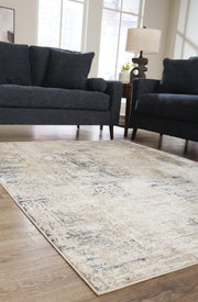 Close-up of Ashley Furniture Gentor 5' x 7' rug showcasing intricate patterns and plush texture on a neutral background.