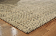 Close-up of Ashley Furniture Janston Rug showcasing detailed woven pattern and soft texture in neutral tones.
