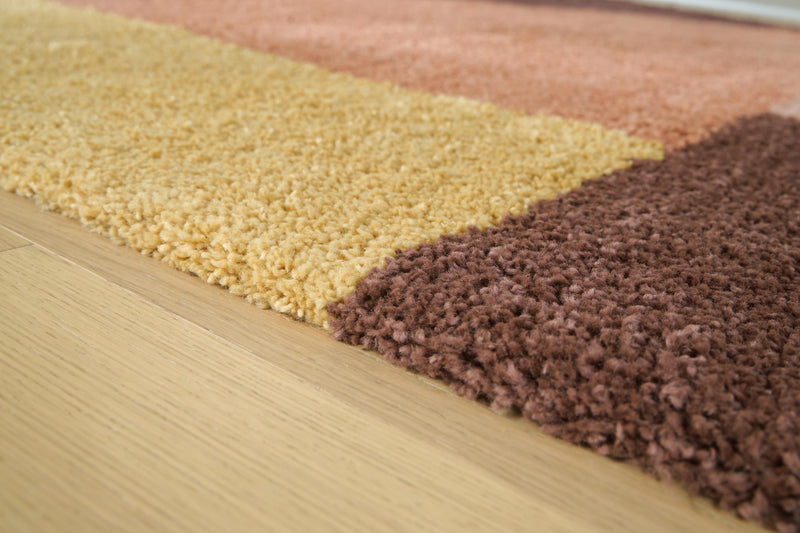Close-up of the Ashley Furniture Gailmore Rug featuring intricate patterns and soft, woven fabric in warm earth tones.