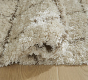 Close-up of Ashley Furniture Wrenlow Rug showcasing detailed woven pattern and rich textures in neutral tones.