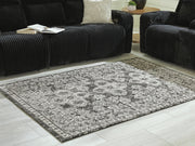 Medium Ashley Furniture Glennisman rug with intricate pattern in neutral tones displayed in a home setting.