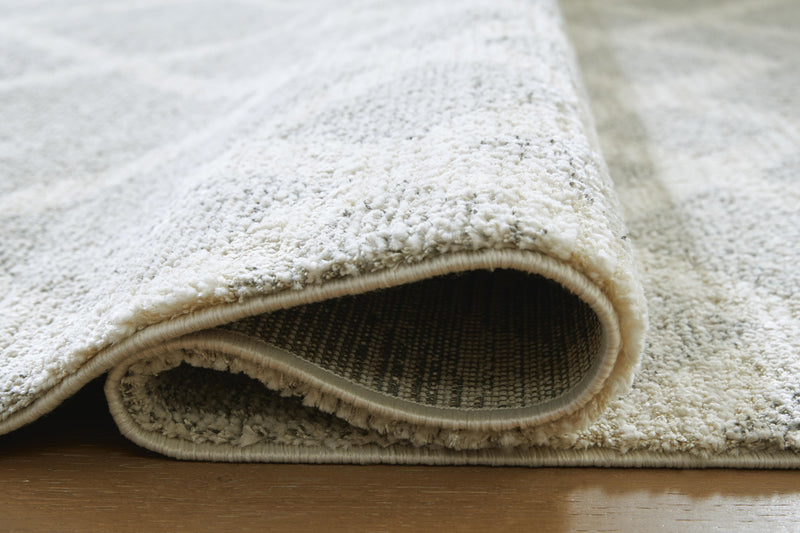Ashley Furniture Unawick Medium Rug showing detailed woven pattern in neutral tones, ideal for living room or bedroom decor.