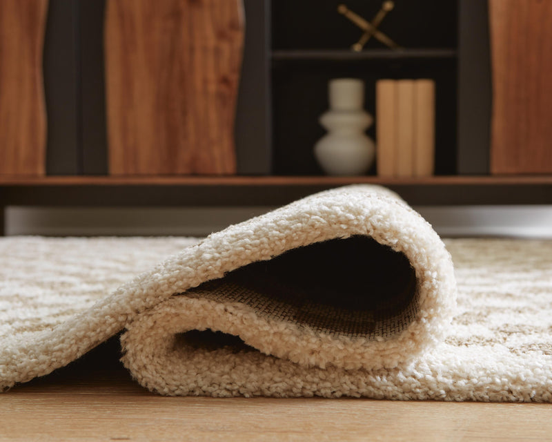 Ashley Furniture Karamen Medium Rug with intricate patterns in neutral tones, showcasing soft fabric and detailed weaving.