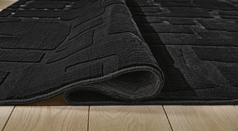 Medium-sized Ashley Furniture Gibbswell washable area rug in 5' x 7' with detailed woven pattern and soft texture.