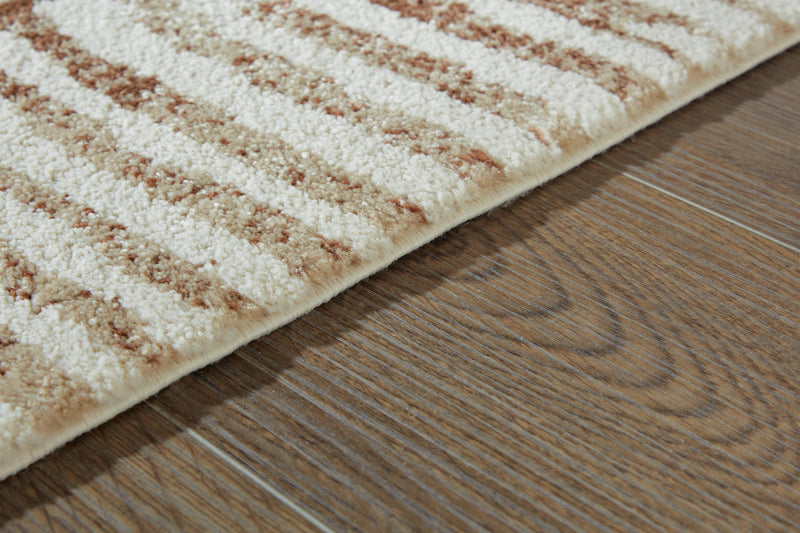 Close-up of the Uduak Rug by Ashley Furniture, showing intricate patterns and soft textured fabric in natural tones.