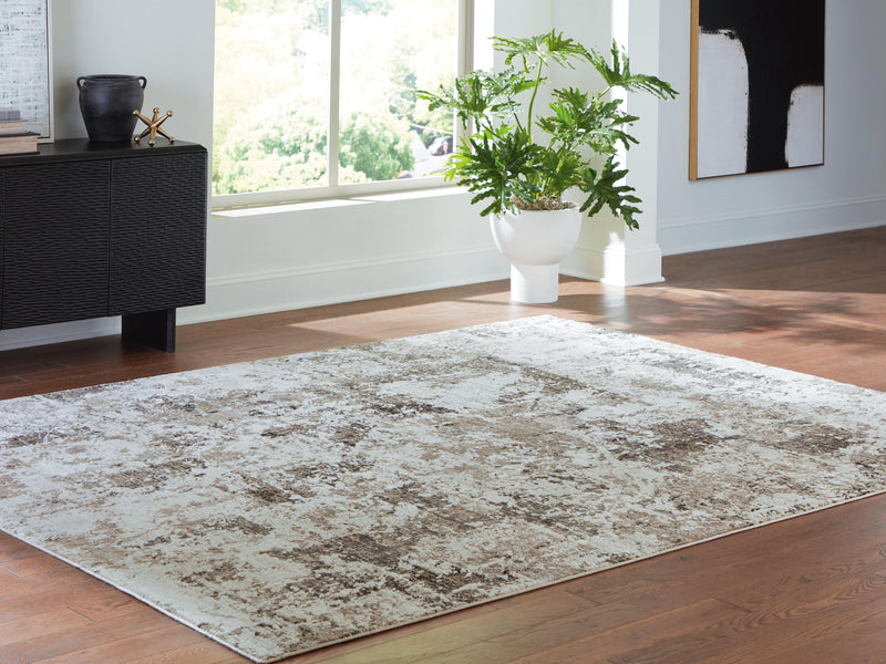Ashley Furniture Barricland Rug with intricate patterns in neutral tones, cropped view showing textured fabric and detailed design.