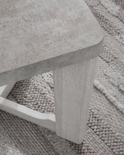 Set of three Garnilly Ashley Furniture end tables with wood finish and modern design, shown in a living room setting.