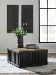 Ashley Furniture Rylandyn lift-top cocktail table with a closed wood surface and storage space, shown in a cropped view.