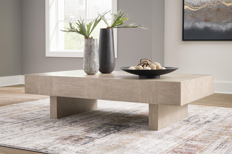 Ashley Furniture Jorlaina coffee cocktail table with a wooden finish and modern design, shown in a stylish living room setting.