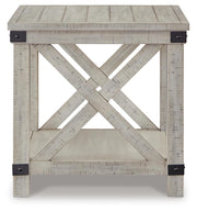 Ashley Furniture Carynhurst end table with a dark wood finish and a single drawer, placed next to a sofa in a living room setting.