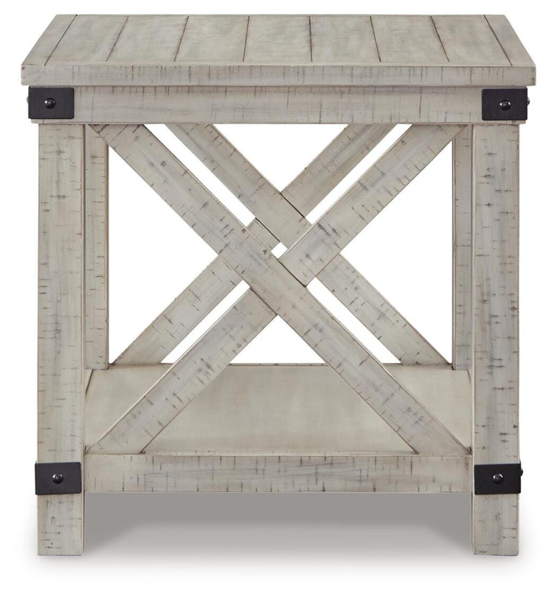 Ashley Furniture Carynhurst end table with a dark wood finish and a single drawer, placed next to a sofa in a living room setting.