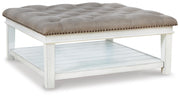 Ashley Furniture Kanwyn upholstered cocktail ottoman coffee table with soft fabric and wooden legs, shown from an angle.
