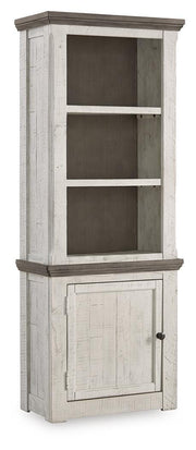 Ashley Furniture Havalance left pier cabinet with closed door, wooden finish, and decorative top detail.