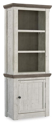 Ashley Furniture Havalance right pier cabinet with closed doors, wooden finish, and decorative details on a modern living room wall.