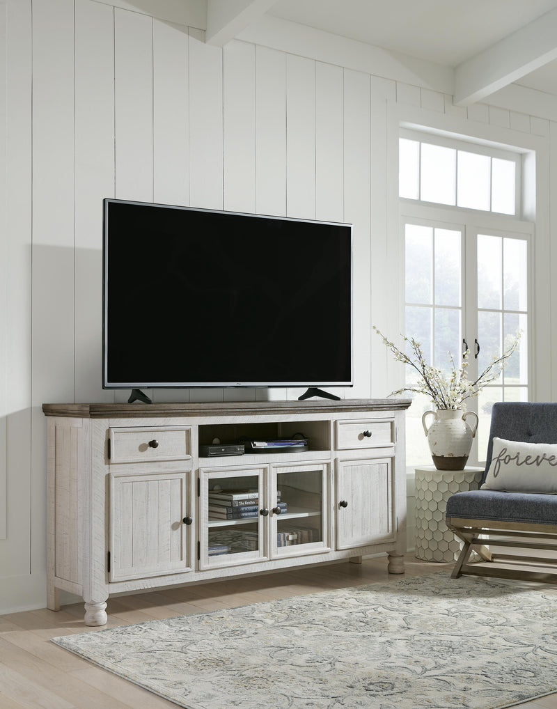 Ashley Furniture Havalance TV Stand with open shelves and storage cabinets, finished in a warm, rustic wood tone.